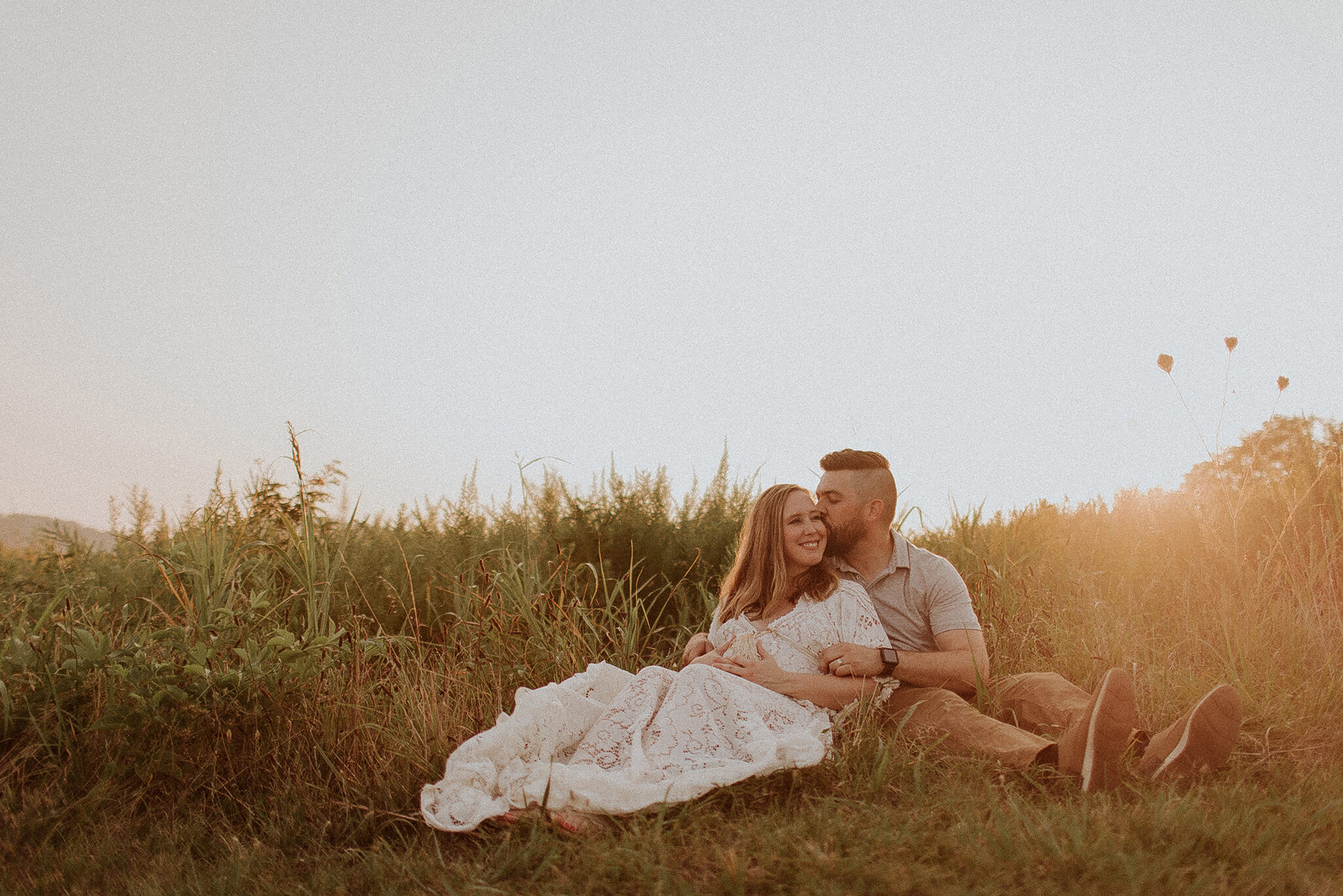 pregnant couple sitting in field