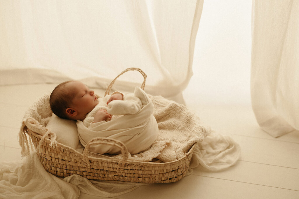 Rylan's Riches photography a Nashville Newborn Photographer photographing a baby swaddled and in a prop in the studio